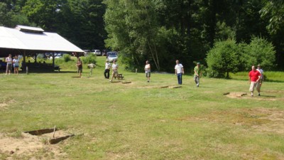 Horseshoe players on the field right next to the pavilion.