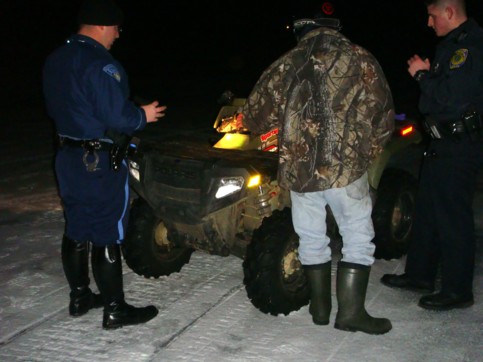 Chucky inspecting his damaged quad with two police officers