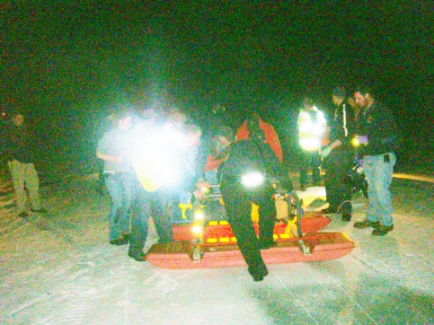 Howard Crow is lifted onto the ice sled.